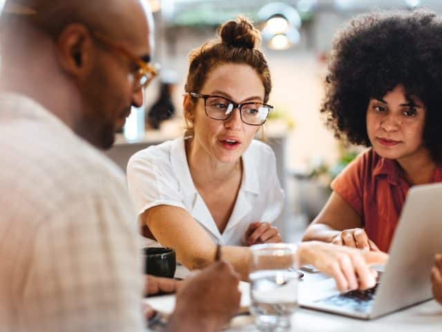 gelukkige medewerkers achter een computer, betrokkenheid en tevredenheid