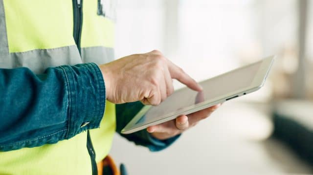 Medewerker in de bouw die een tablet in zijn hand heeft