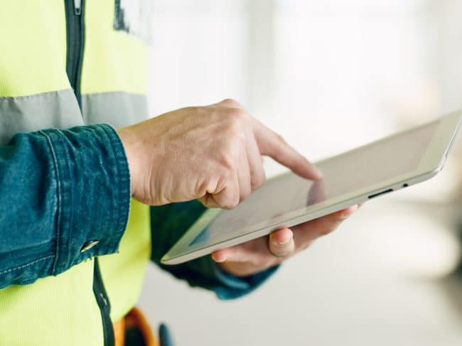 Medewerker in de bouw die een tablet in zijn hand heeft